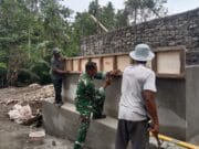 Anggota Kodim 1505/Tidore Bersama Warga Pasang Besi dan Papan Cor Jembatan Garuda